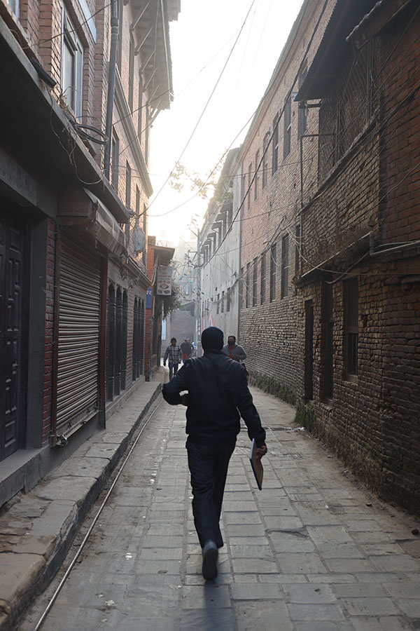 Photo of a Narrow, Brick Lined Street, with Striding Man.